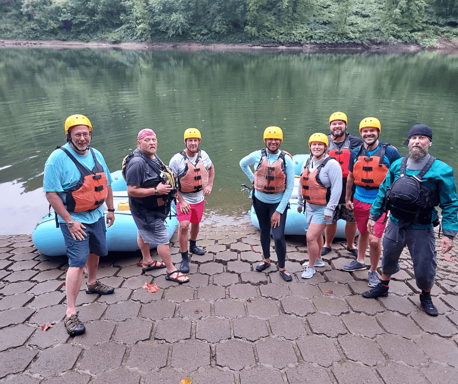 Group of people with life vests and helmets about to go rafting
